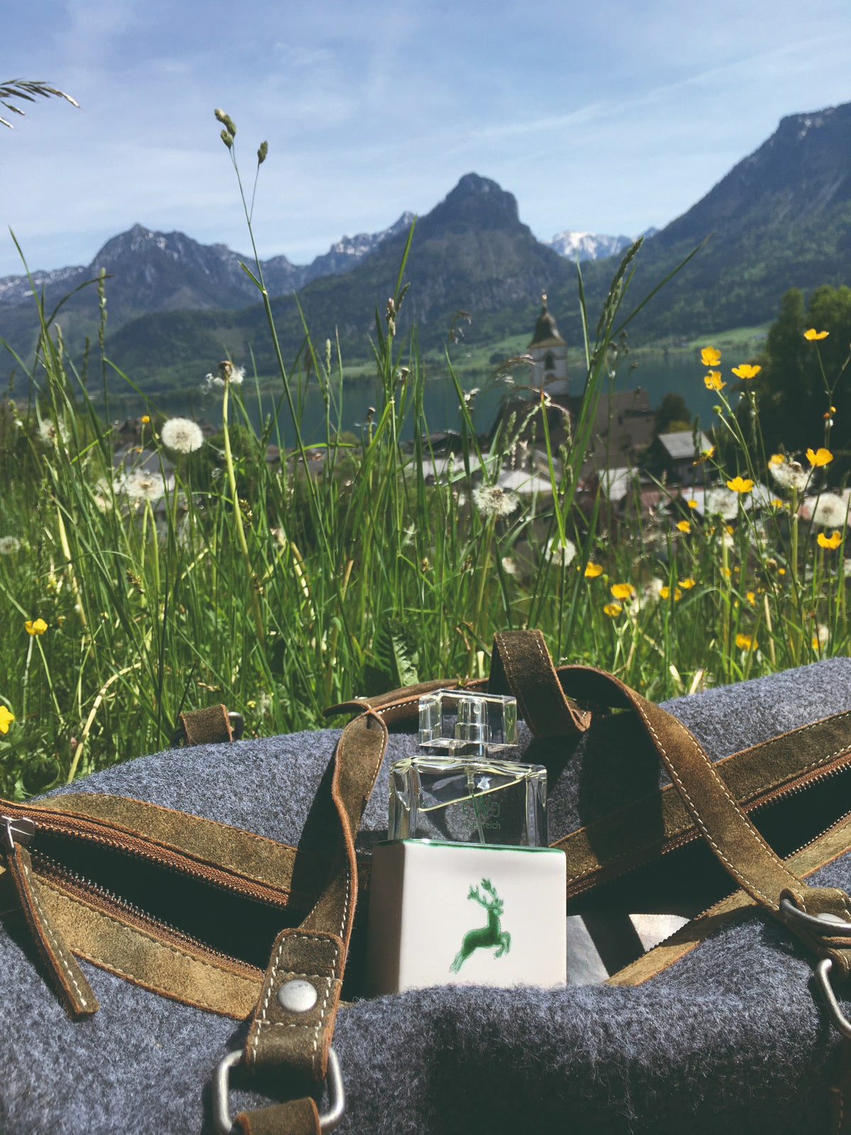 CWC GRÜNER HIRSCH 75 ml auf einer Tasche vor Bergen am Wolfgangsee